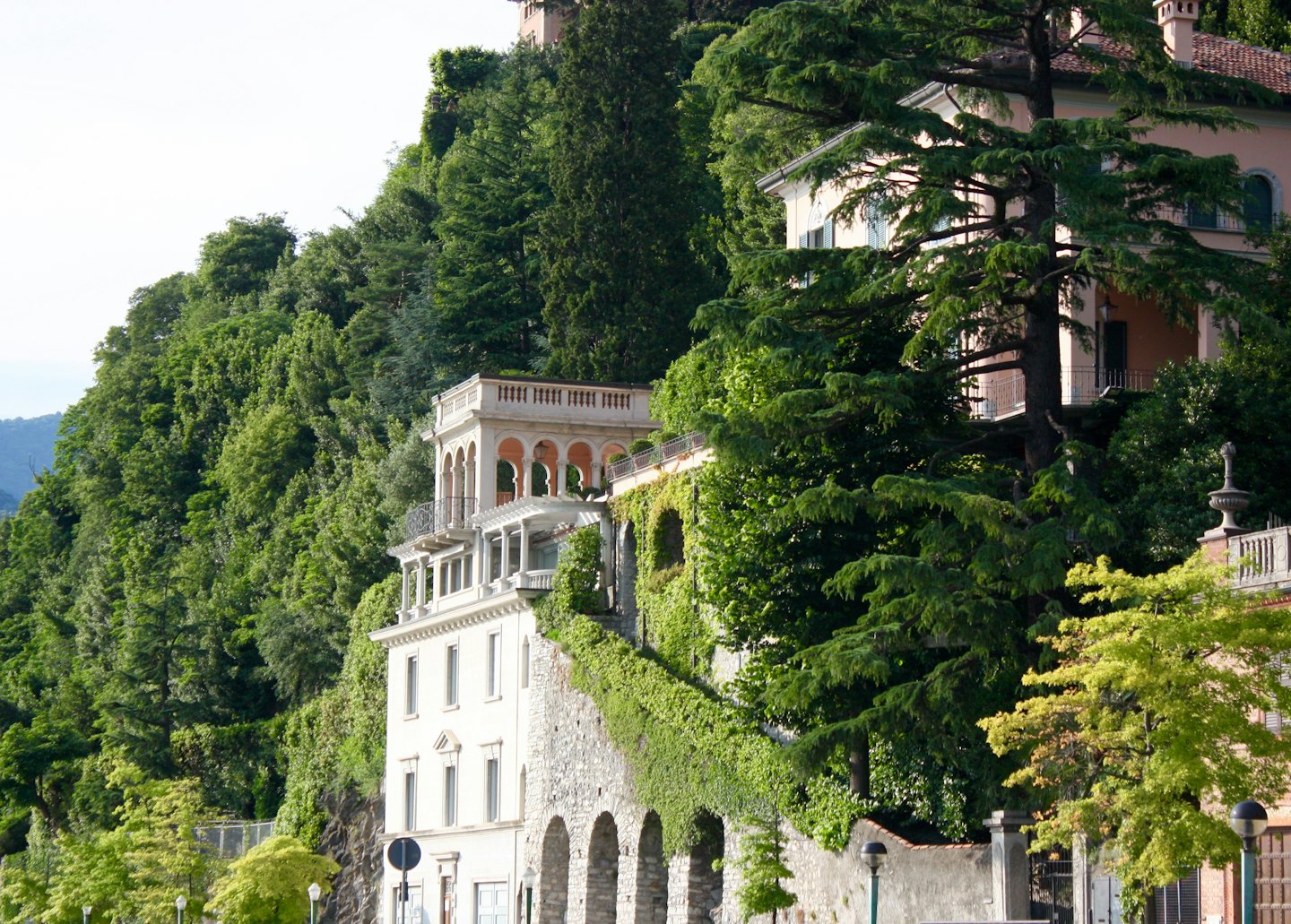 Ville eleganti con muri in pietra coperti d'edera su un pendio boscoso.