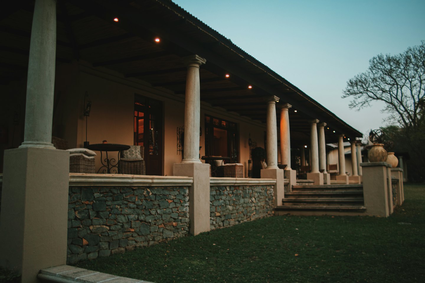 Veranda coperta con colonne e luci al tramonto.