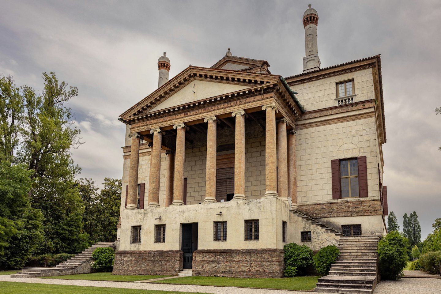 Villa storica con colonne e portico circondata da alberi.